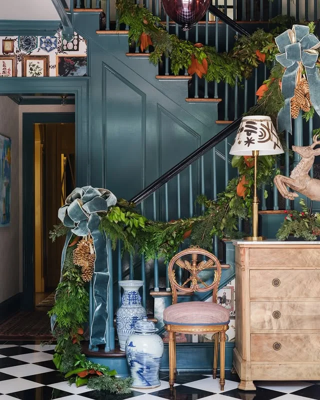 Teal painted staircase draped with Christmas garland and velvet bows