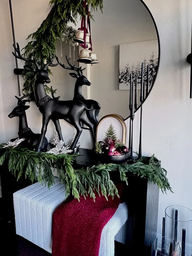 Dark glam console table with black reindeer statues and cascading greenery