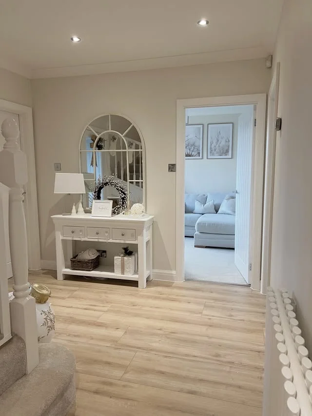 Serene white entryway with arched mirror, wreath, and simple console table