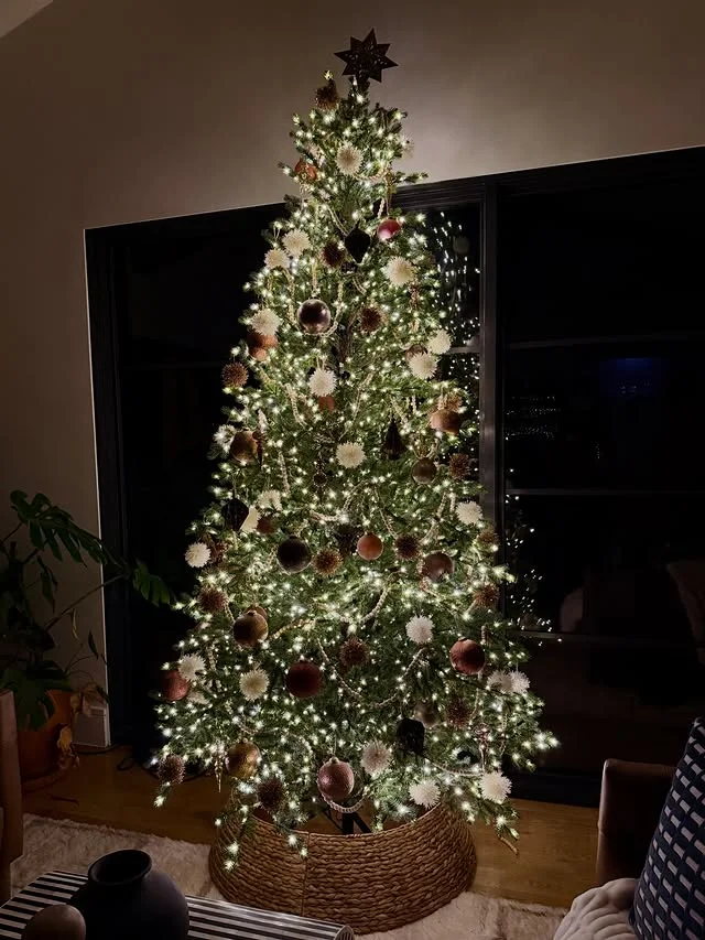 Neutral Christmas tree with cream ornaments in a woven tree collar