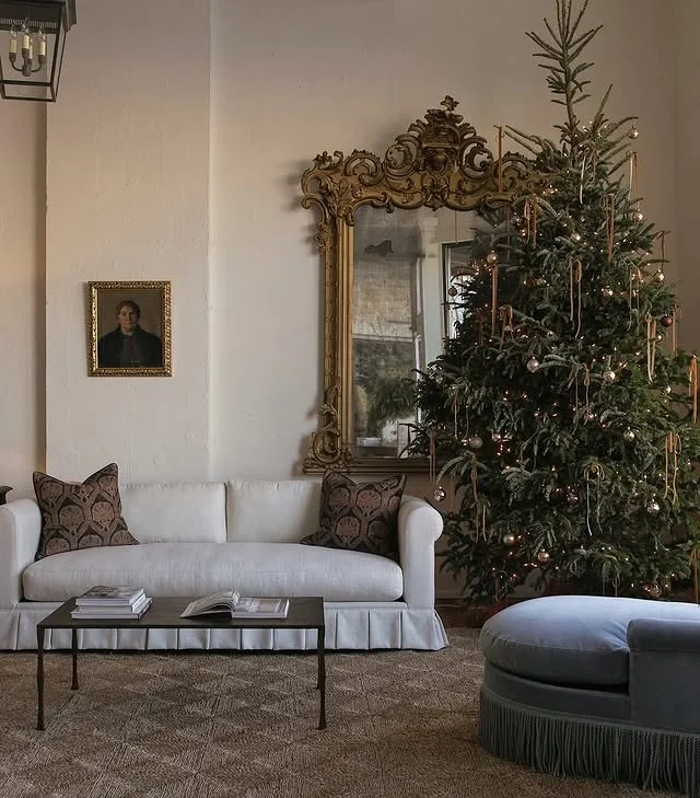 Natural spruce Christmas tree beside a gilt mirror in a calm living room