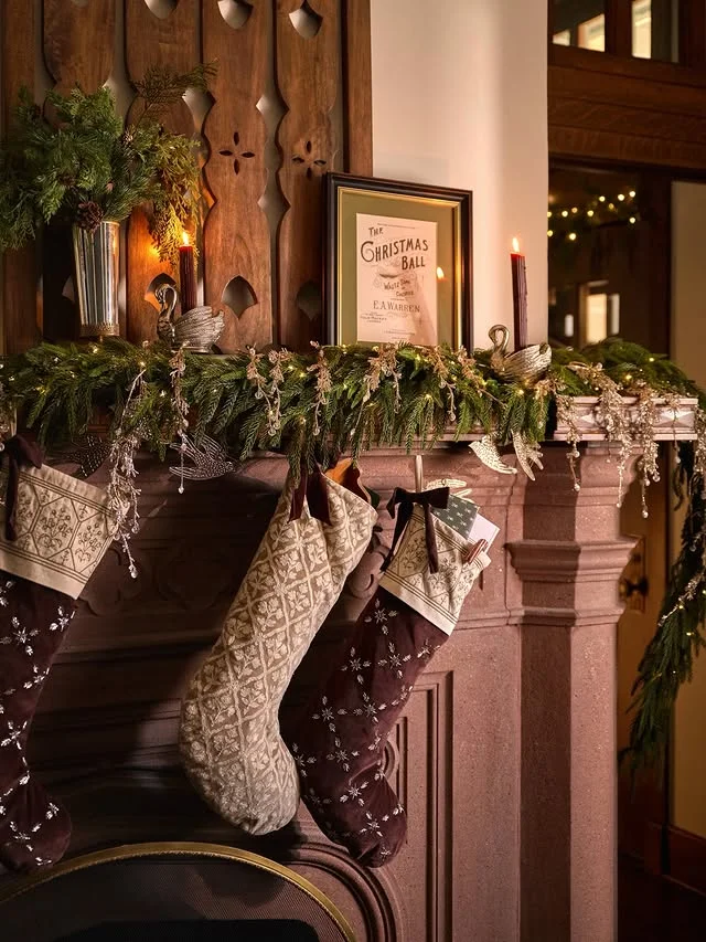 Rustic wood mantel with knit stockings, red berries, and candles