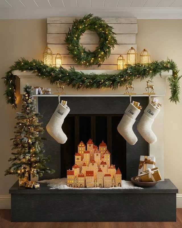 Black mantel with an oversized wreath, lanterns, and stockings