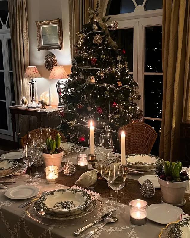Vintage Christmas table with floral china, candles, and a lit Christmas tree