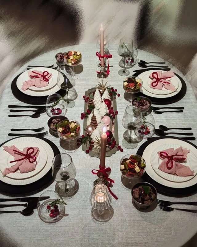Elegant Christmas table with pink bow napkins, black chargers, and candles