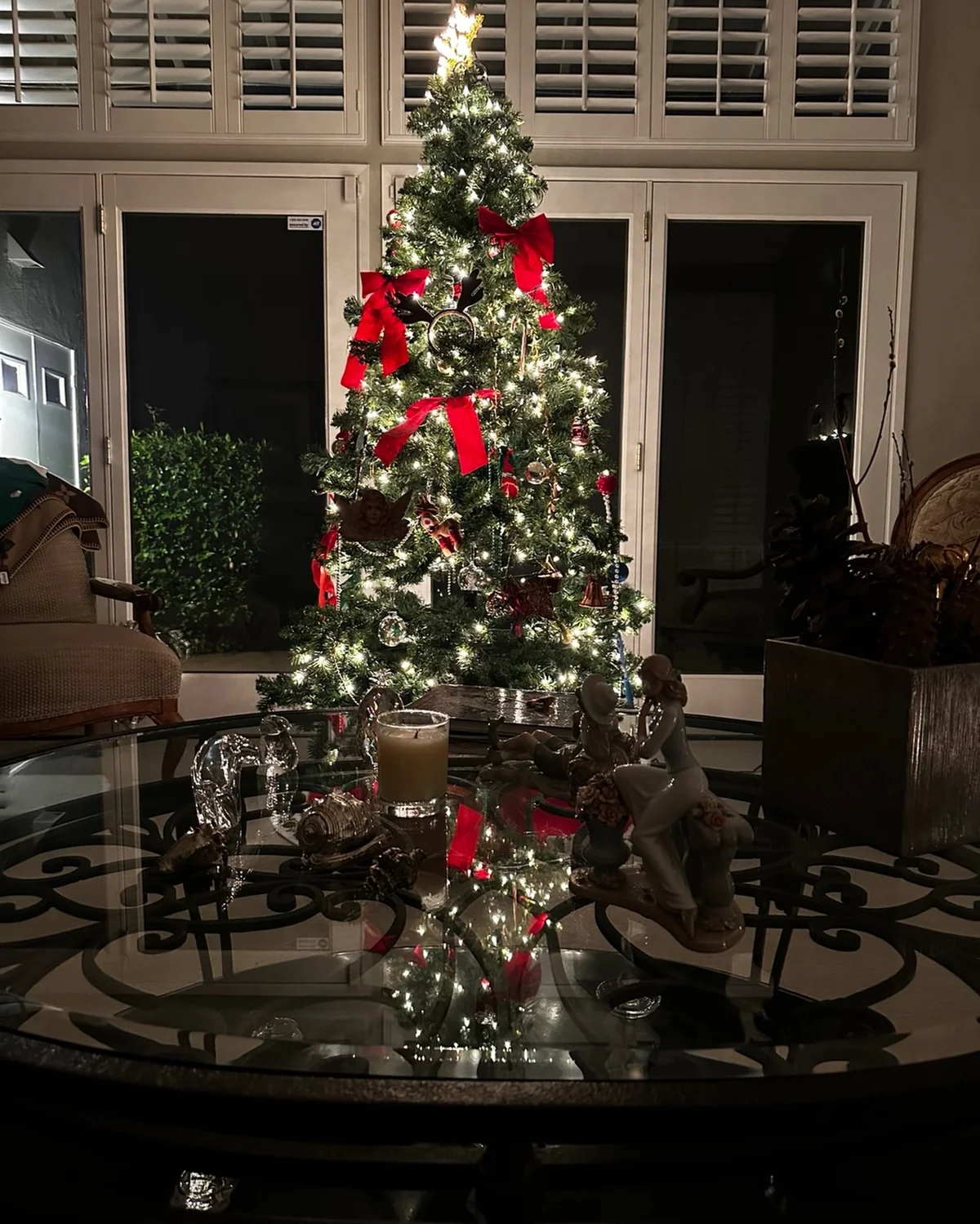 Christmas tree decorated with red bows and glowing lights in a living room