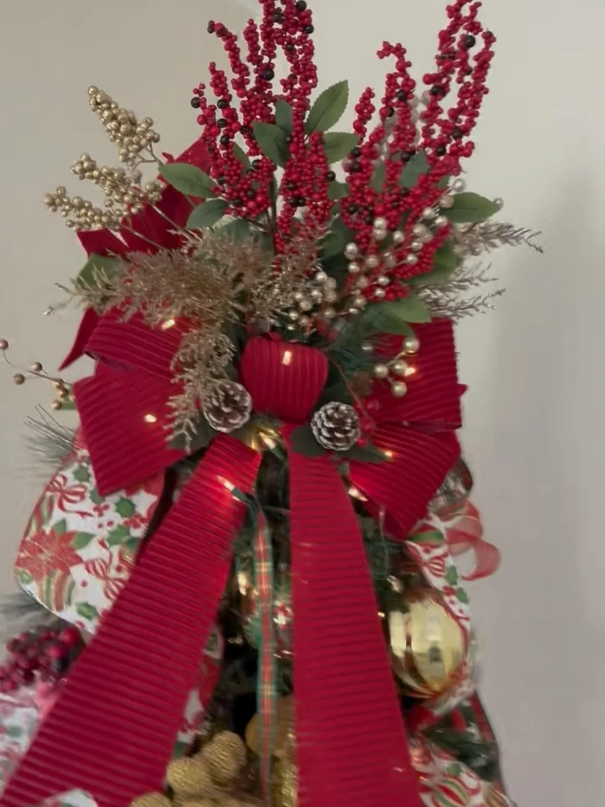 Close up of large red velvet bow with frosted pinecones on christmas tree