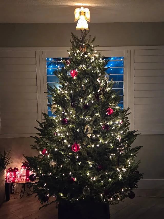 Christmas tree with glowing angel tree topper and red ornaments