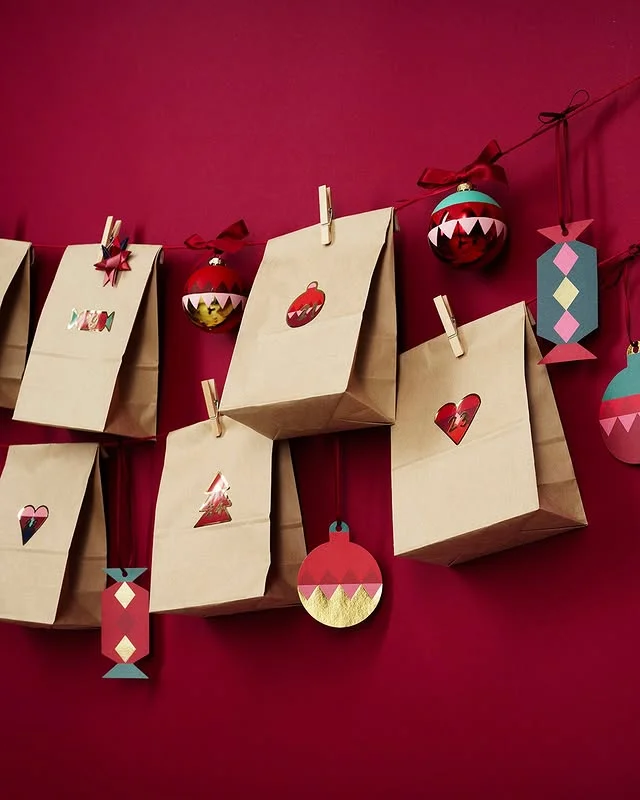 Brown paper bag advent calendar hung on red string against a red wall