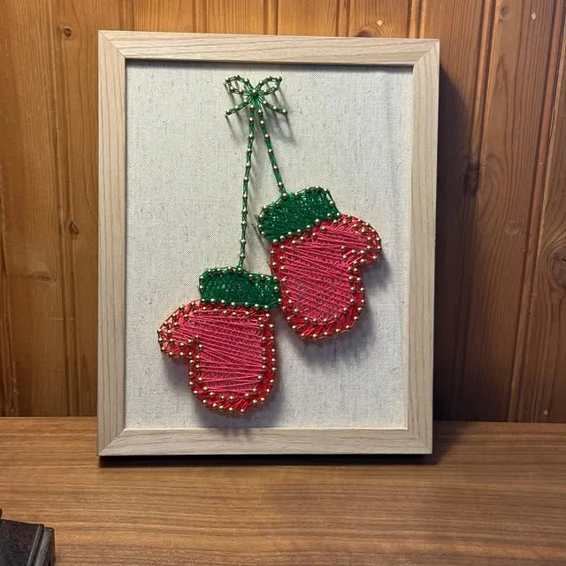 Framed string art of pink mittens with green cuffs