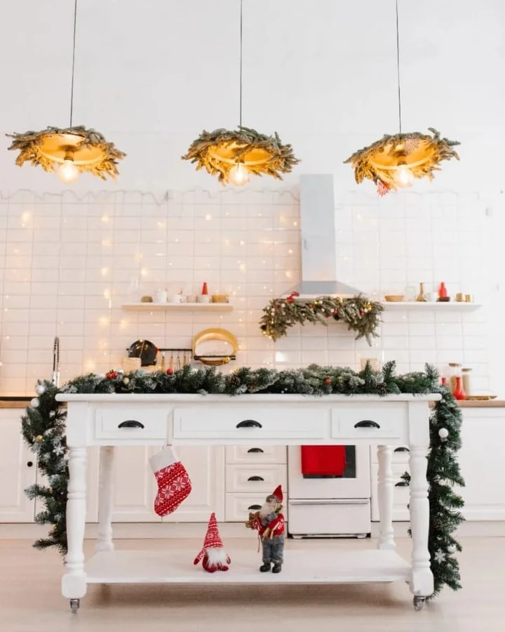 White kitchen island draped in frosted evergreen garland with gnomes