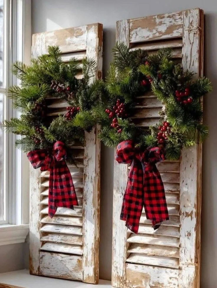 Pair of distressed white shutters decorated with evergreen wreaths and buffalo check bows