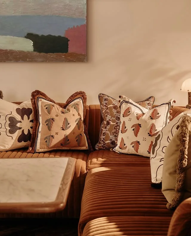 Layered throw pillows on a caramel velvet sofa