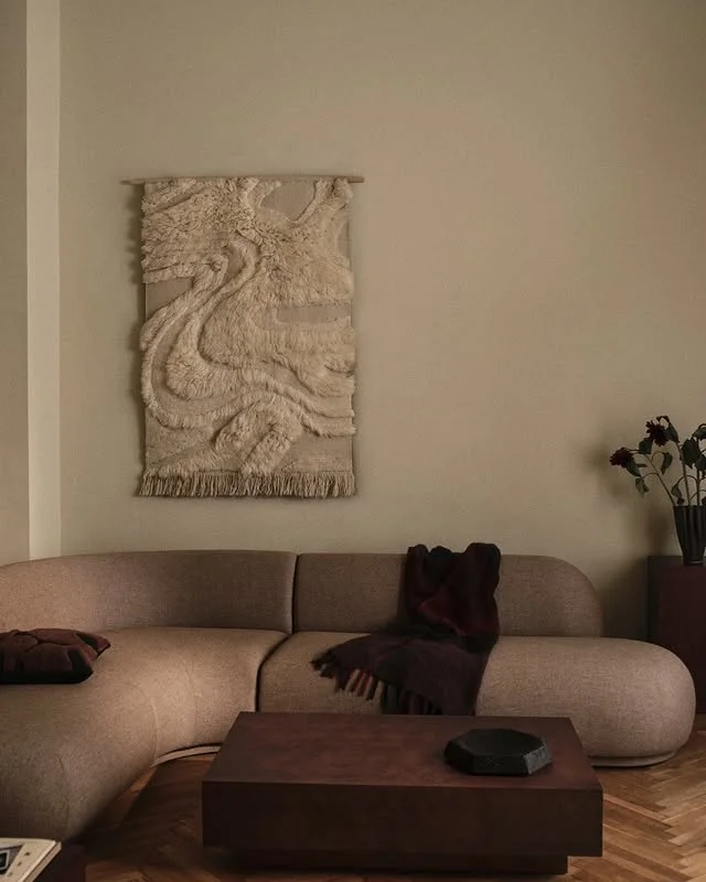 Modern living room with curved beige sofa and woven wall hanging
