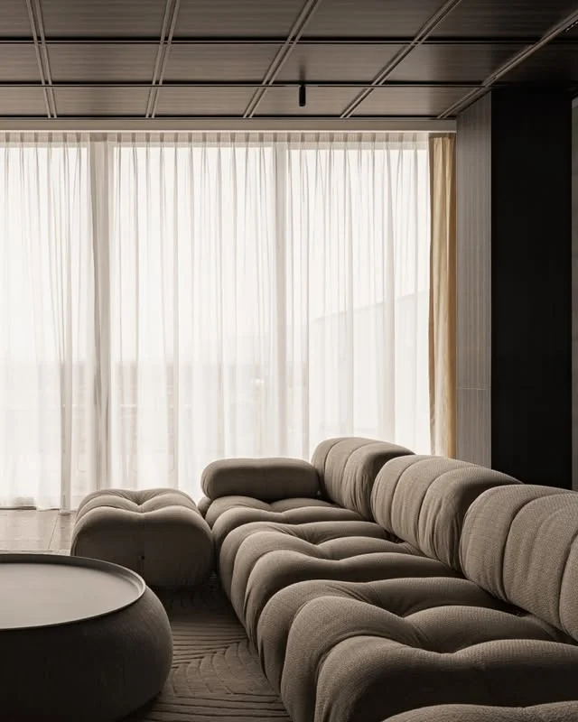 Minimalist living room with tufted sofa and sheer floor-to-ceiling curtains