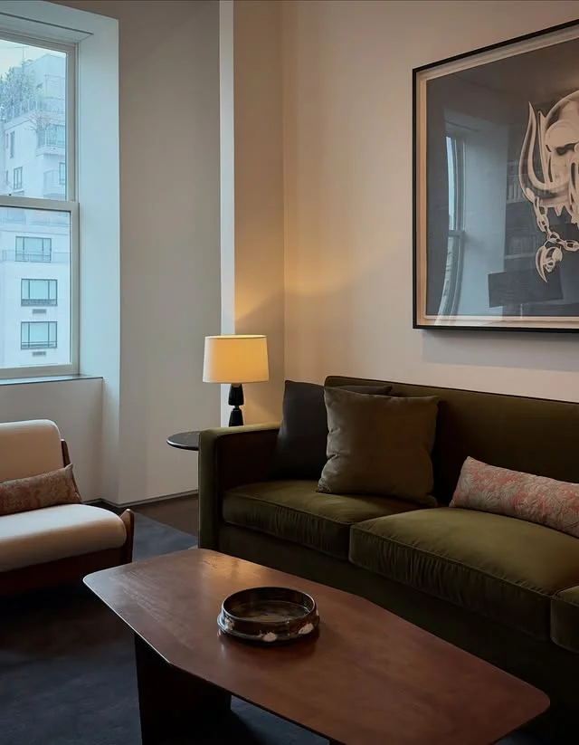 Olive velvet sofa with wood coffee table under framed artwork