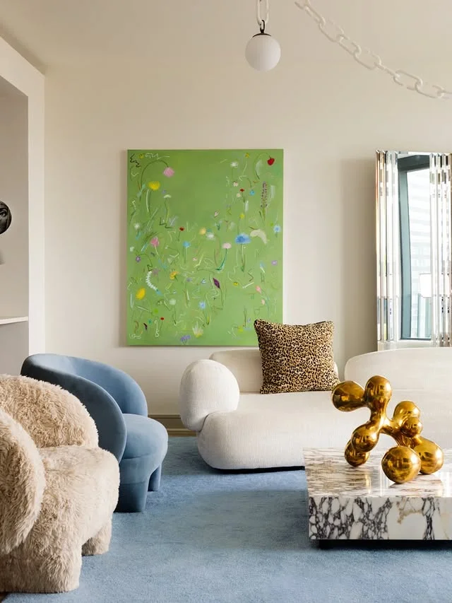 Curved white sofas with marble coffee table and abstract art