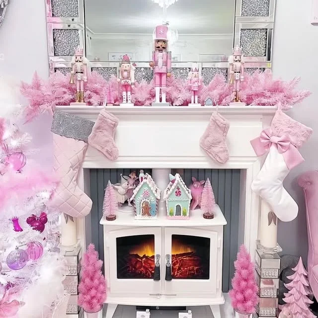 White mantel with pink nutcracker figurines, pink stockings and a fluffy pink garland