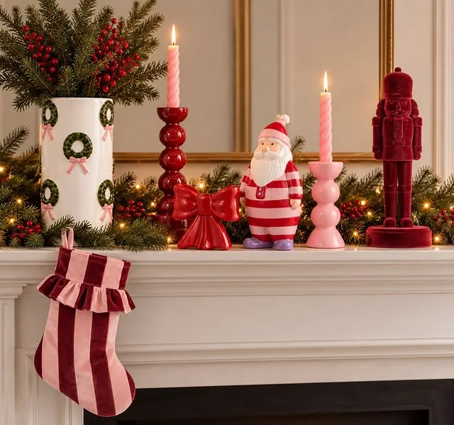 Mantel styled with pink taper candles, a pink Santa figurine, and a pink striped stocking