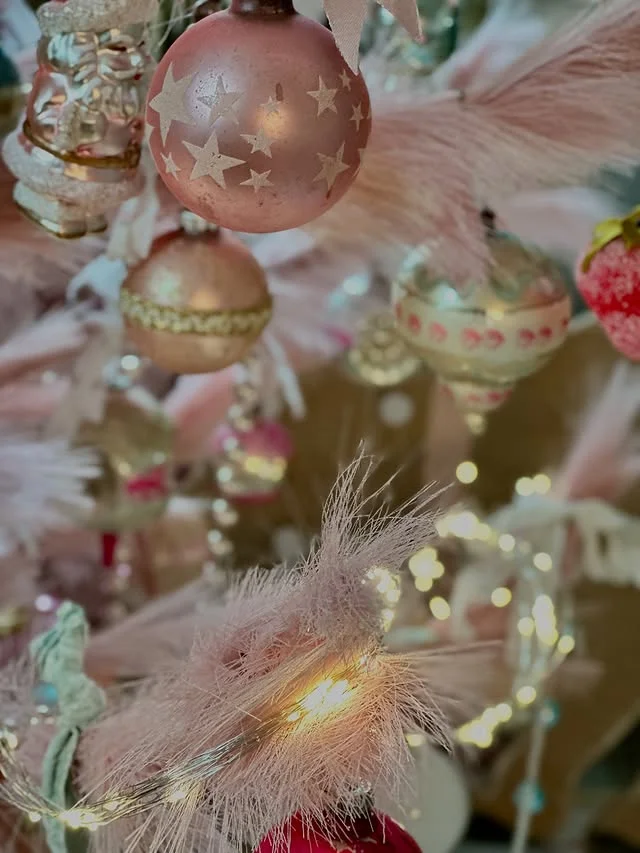 Close-up of rose gold and blush Christmas ornaments with star patterns on a flocked tree