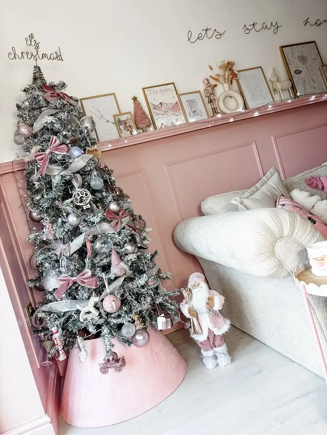 Slim Christmas tree with pink and silver ornaments in a corner with pink panelled walls