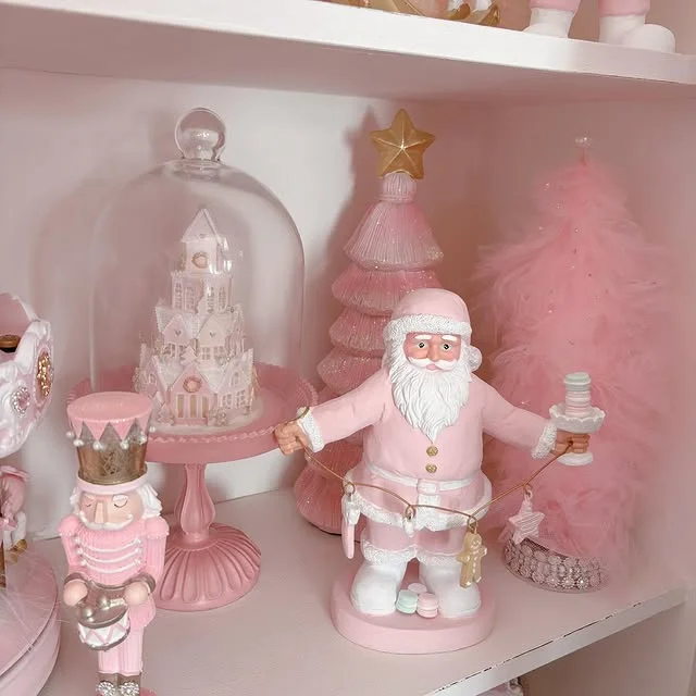 Pink shelf styled with a pink Santa figurine, a glass cloche with a glitter house, and a small pink tree