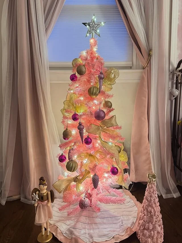 Pink Christmas tree decorated with gold ribbon, magenta ornaments and a lit star topper